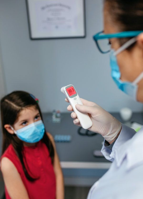 Female pediatrician looking at infrared thermometer after taking temperature to a girl